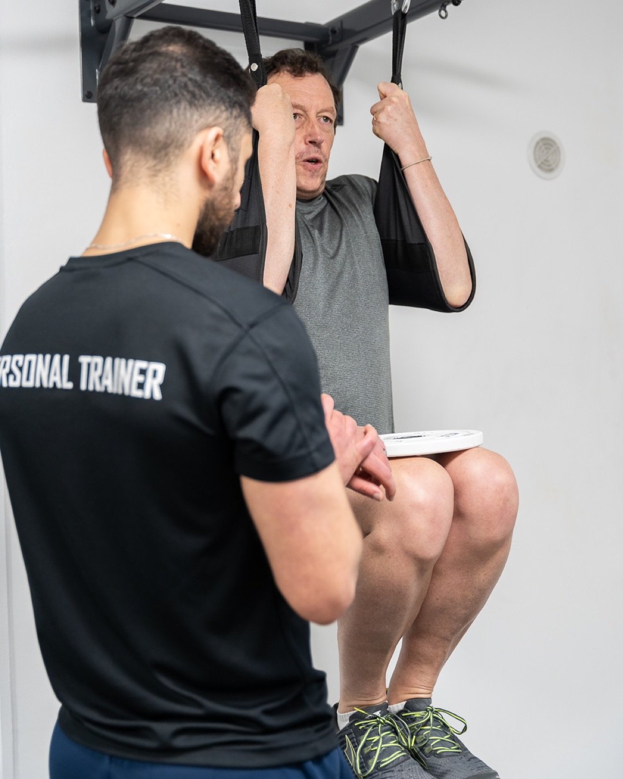 Moti accompagne un client pendant un exercice de gainage suspendu